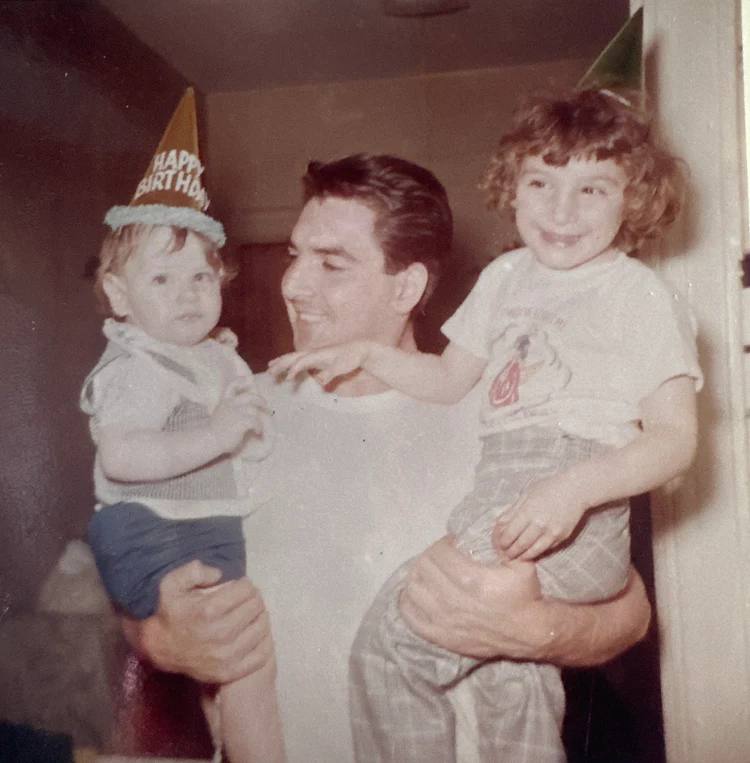 Papa holding young children in birthday hats